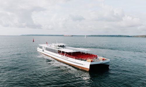 The Silver Raven, a white electric boat with an open deck of red seats, sailing by day