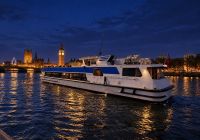 Thames cruise boat at night in front of the lit-up Big Ben and Houses of Parliament