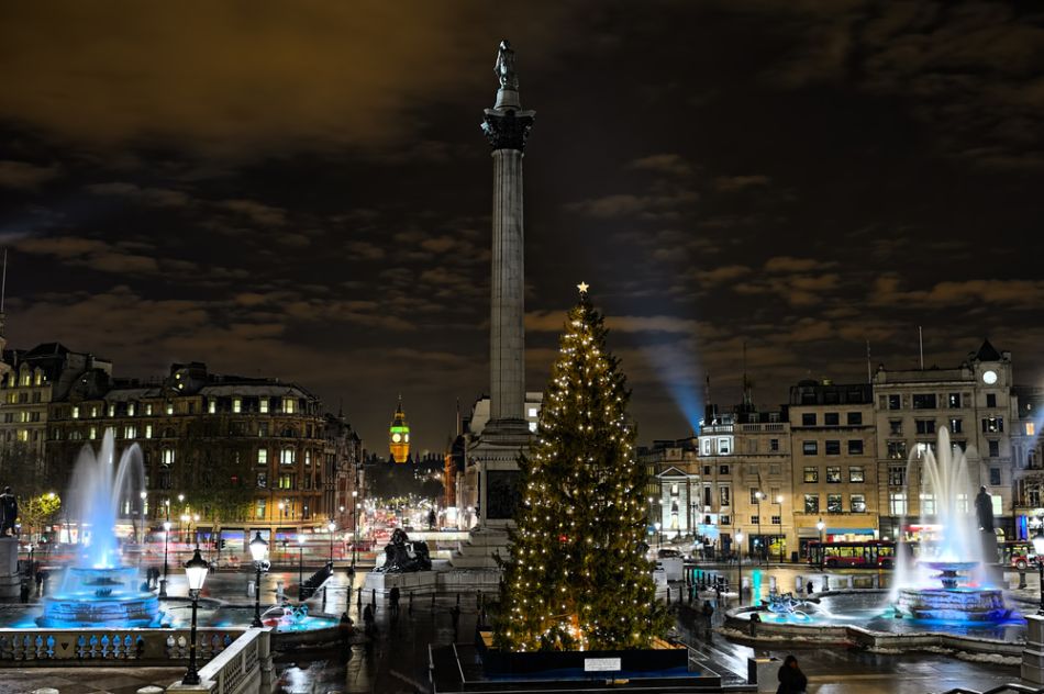 The Norwegian Christmas tree lit up in Trafalgar Square at night, with the fountains and Nelson's Column