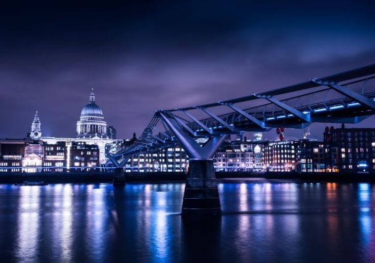 St Paul’s Cathedral and the Millennium Bridge lit up at night, reflected in the Thames
