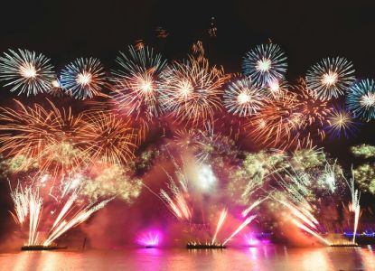 Fireworks launched from barges over the water
