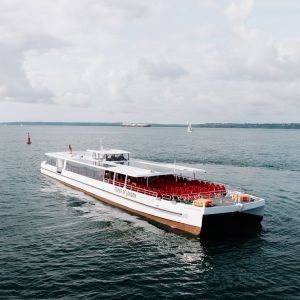 The Silver Raven, a white electric boat with an open deck of red seats, sailing by day