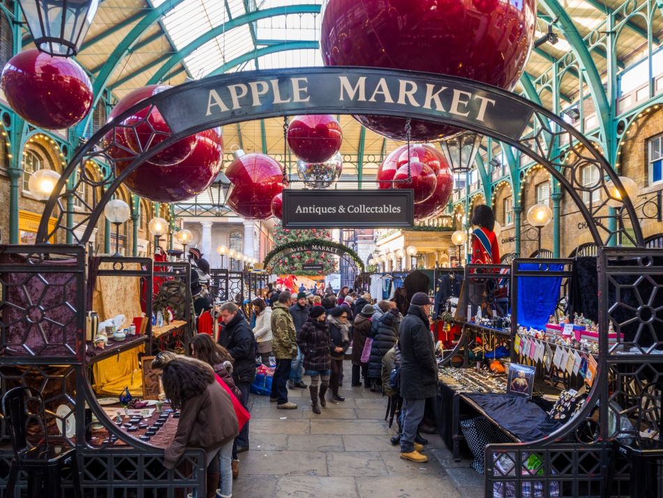 Grandes boules rouges suspendues sous la verrière de l'Apple Market de Covent Garden, au-dessus des étals et des visiteurs