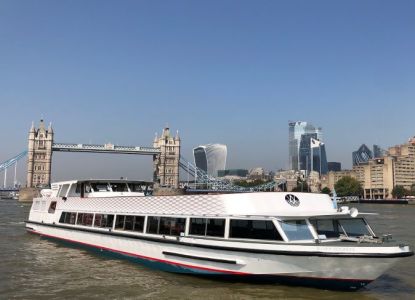 The Silver Sockeye, a white Thames cruise boat, in front of Tower Bridge by day