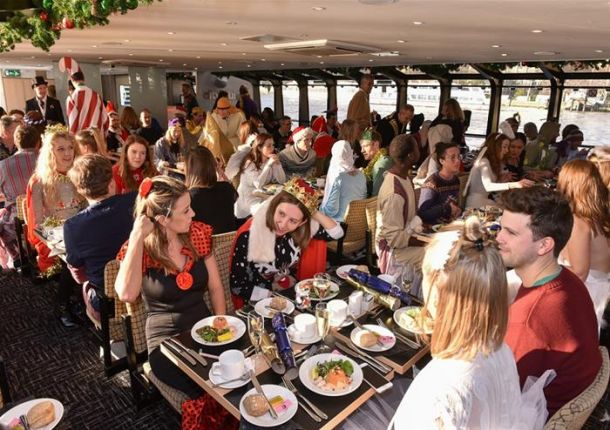 Convives au déjeuner de Noël dans le salon chauffé d’un bateau sur la Tamise