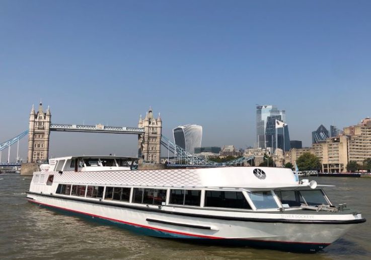 The Silver Sockeye, a white Thames cruise boat, in front of Tower Bridge by day