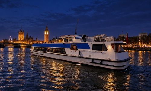 Thames cruise boat at night in front of the lit-up Big Ben and Houses of Parliament