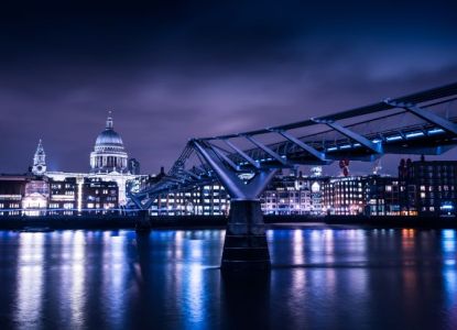 St Paul’s Cathedral and the Millennium Bridge lit up at night, reflected in the Thames