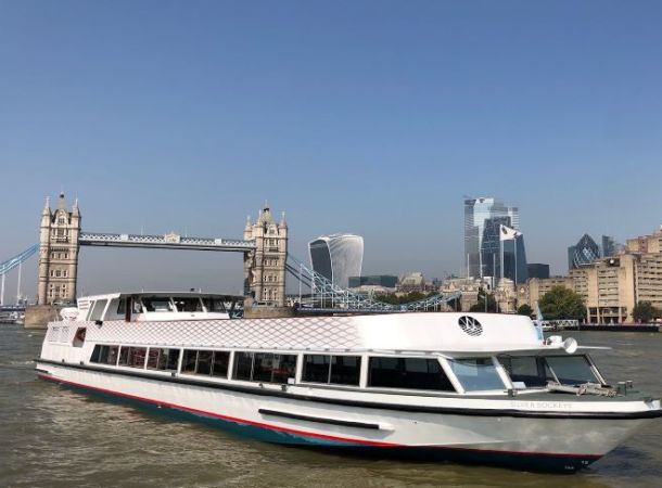 The Silver Sockeye, a white Thames cruise boat, in front of Tower Bridge by day